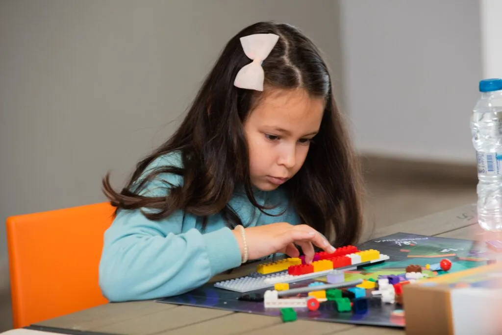 Момиче сглобява робот от LEGO